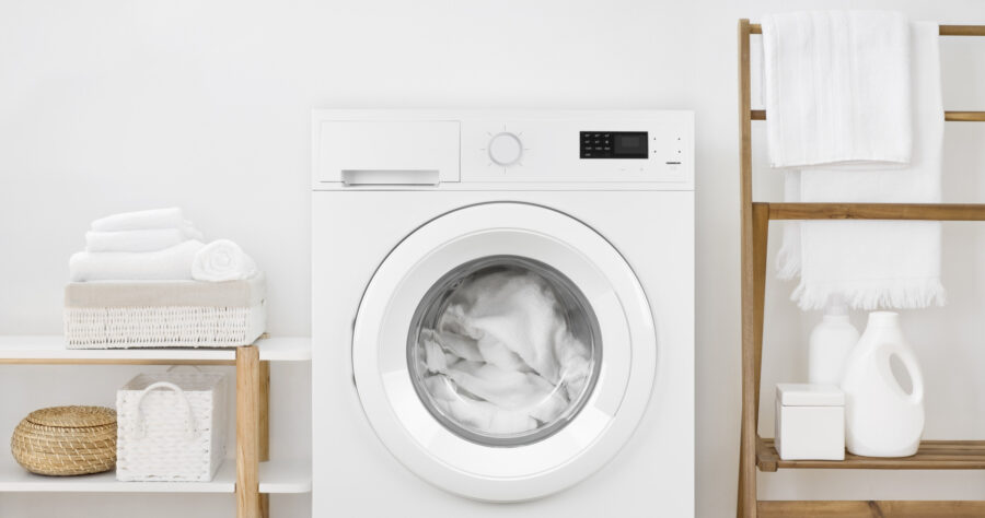 A close-up of a white washing machine in a white bathroom