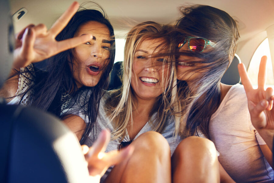 Three girls laughing in the back of the car