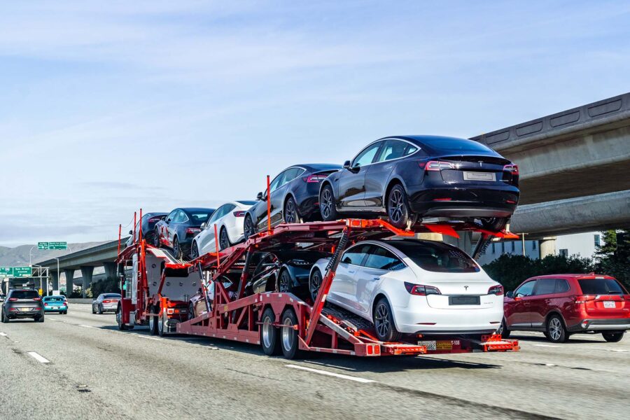 January 19, 2019 San Bruno / CA / USA - Car transporter carries Tesla Model 3 new vehicles along the highway in San Francisco bay area, back view of the trailer;