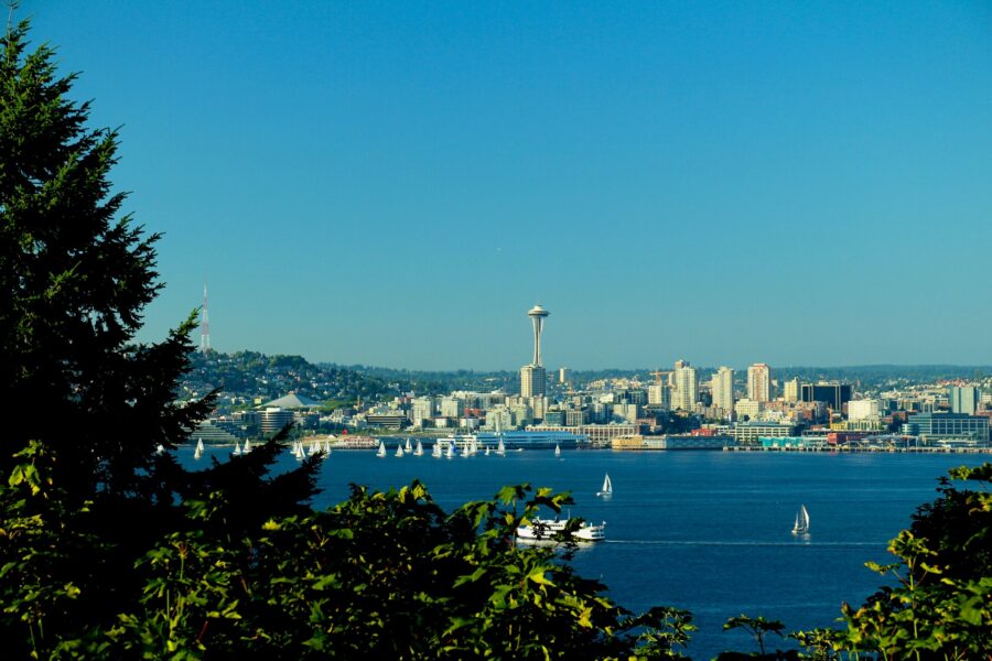 Scenic view of Seattle featuring the sea and majestic mountains under a blue sky.